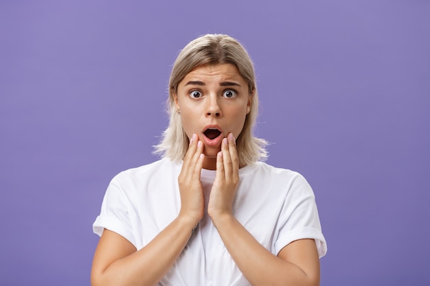 Waist-up shot of worried and shocked woman expressing empathy frowning holding hands