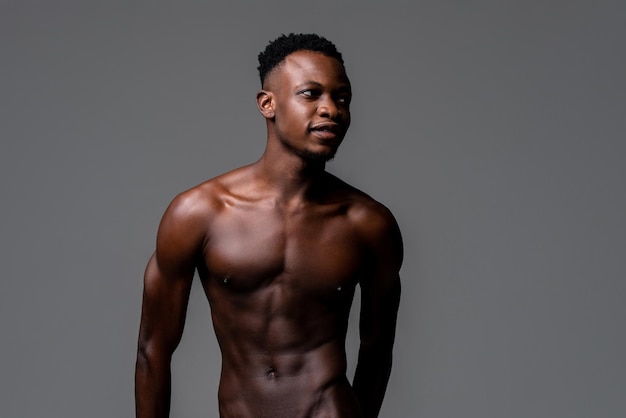 Waist up studio portrait of shirtless young lean fit African man in isolated light gray background