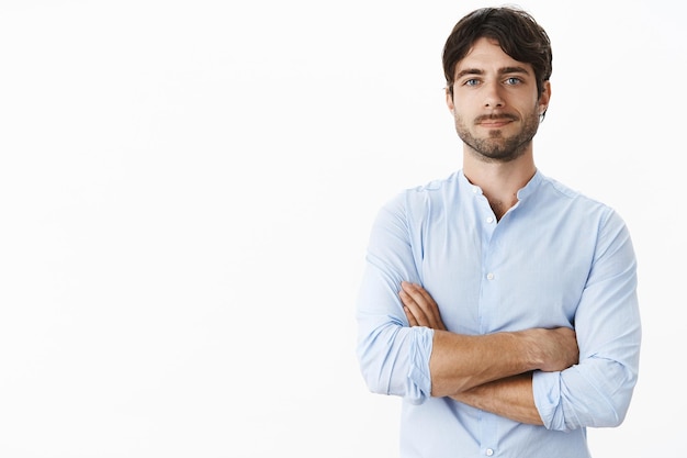 Waistup shot of confident successful handsome entrepreneur with blue eyes and bristle in blue shirt holding hands crossed on chest