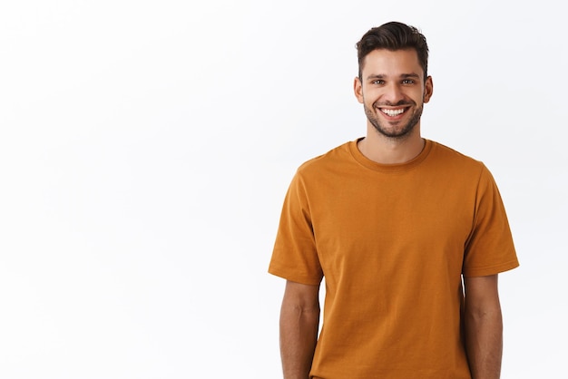 Waistup shot pleasant friendly young attractive bearded guy in brown tshirt talking casually with friends at party smiling satisfied showing happy positive emotion standing white background