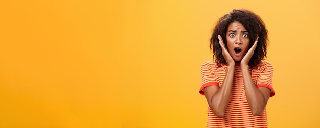 Waistup shot of shocked concerned panicking africanamerican woman with afro hairstyle in trendy tshi