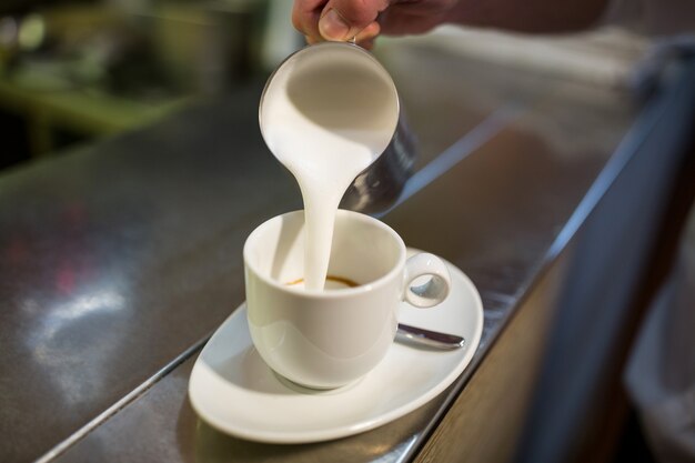 Waiter adding milk to coffee