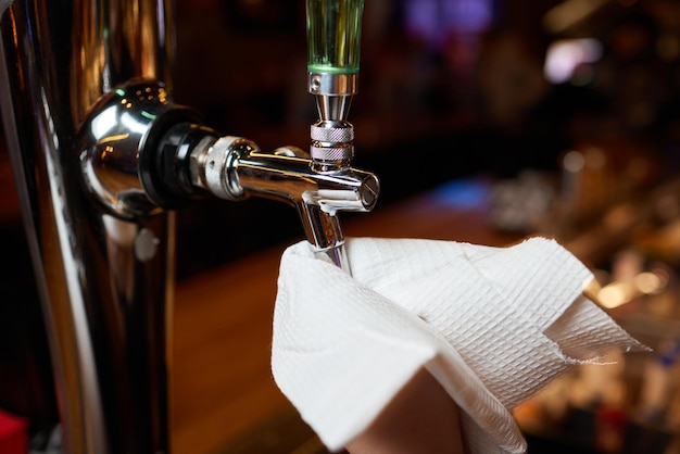 Waiter or bartender cleaning beer taps on the counter in pub and restaurant