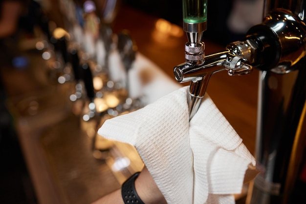 웨이터 또는 바텐더가 펍과 레스토랑의 카운터에서 맥주 탭을 청소합니다.