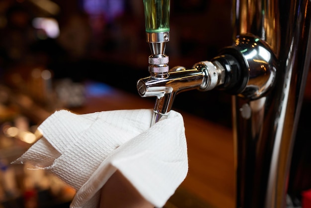 Waiter or bartender cleaning beer taps on the counter in pub and restaurant