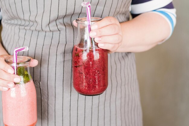 Waiter brings bottles of smoothie to customer Fruit drinks from strawberry and wineberry with mint refreshment in summer period detox healthy food close up picture