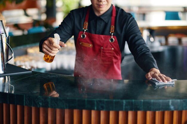 Photo waiter cleaning bar counter