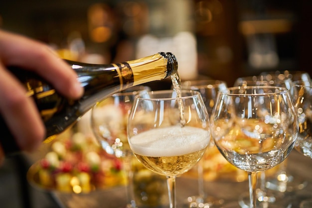 a waiter in gloves pours champagne into glasses closeup