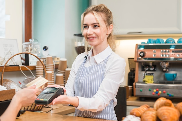 사진 고객이 커피 숍에서 신용 카드를 표시하는 동안 신용 카드 슬쩍 기계를 들고 웨이터