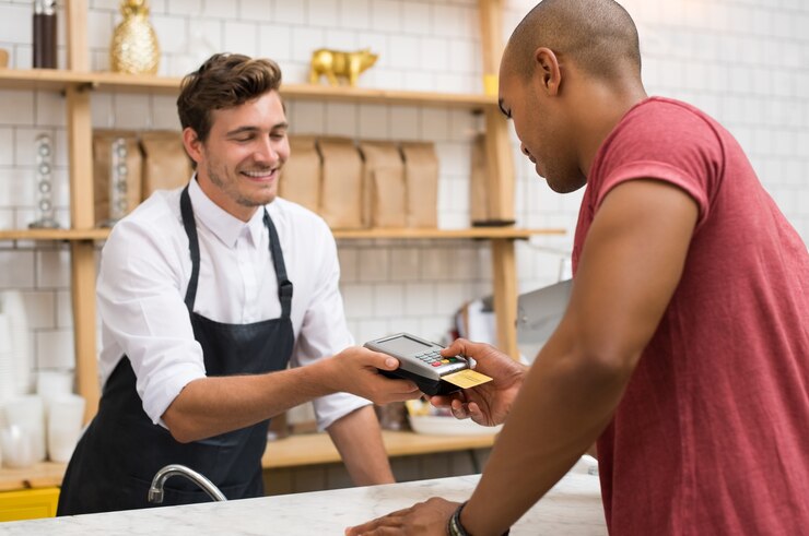 Waiter holding credit card swipe machine while customer typing code