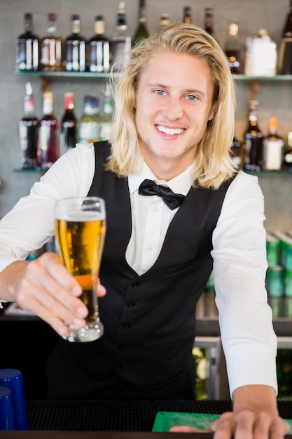 Waiter holding glass of beer at bar counter