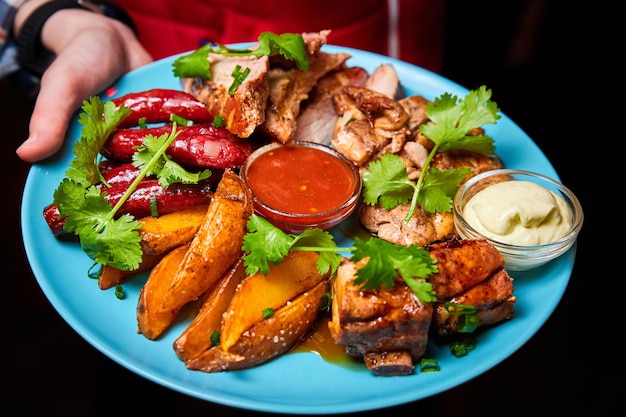 Waiter holding a large platter with Shish kebab grilled potato and sauces