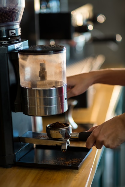 Waiter holding portafilter filled with ground coffee