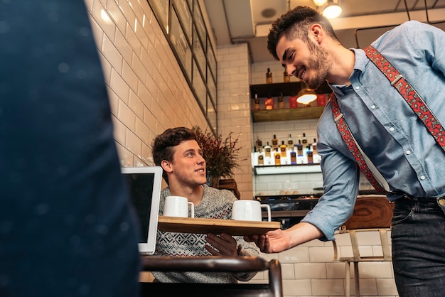 Waiter holding a tray with coffees in the bar.