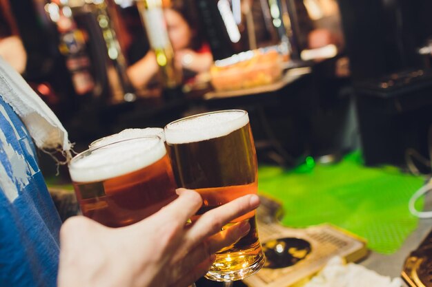 Foto il cameriere tiene i bicchieri di birra in mano in un bar o in un pub