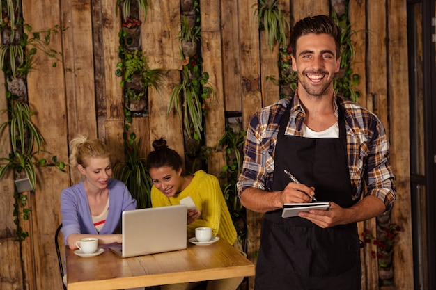 A waiter is taking the order in front of the two friends