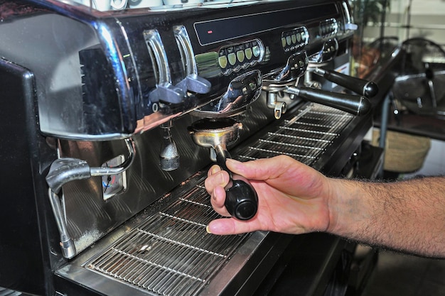 The waiter makes a coffee in the espresso machine