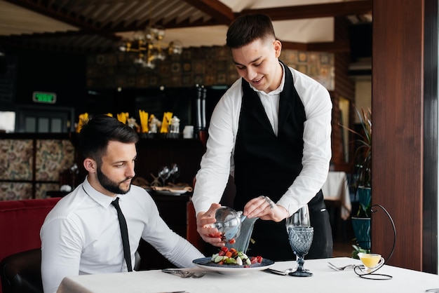 The waiter makes an exquisite serving of seafood salad tuna and black caviar in a beautiful serving on the table in the restaurant Exquisite delicacies of haute cuisine closeup