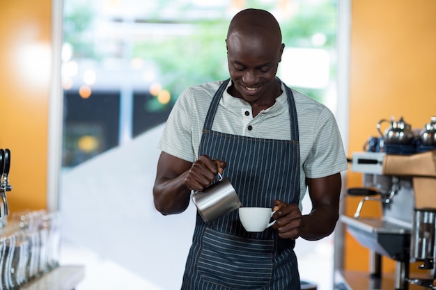 Waiter making cup of coffee at counter
