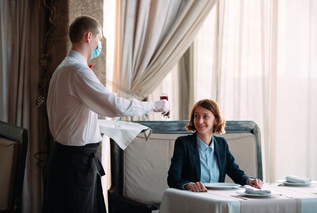 waiter in a medical mask serves Latte coffee