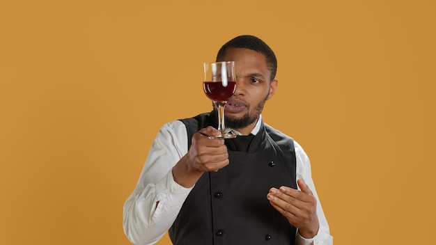 Waiter offering a glass of wine to customers waiting for food at the table