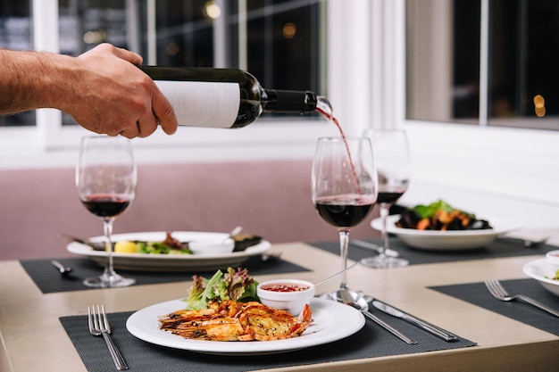 Waiter pouring red wine into wineglass