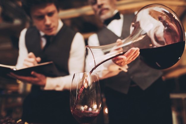 Waiter Pours Wine from Decanter into Glass.