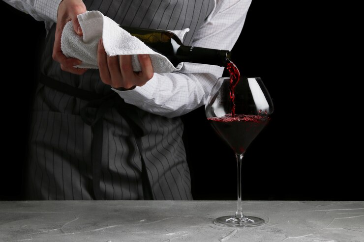 Photo the waiter pours wine in glass on dark background