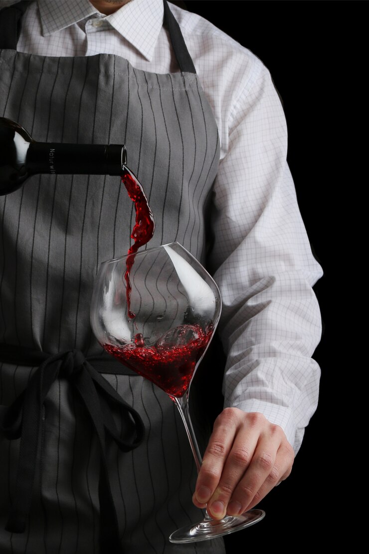 Photo the waiter pours wine in glass on dark background