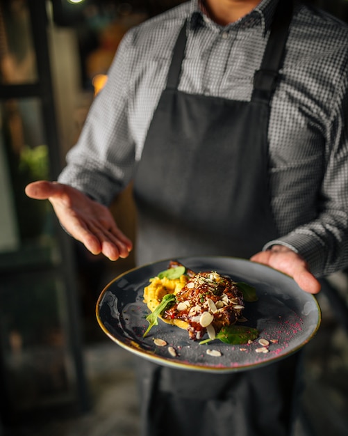 The waiter presents a fried chicken and mashed potato