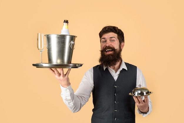 Waiter in restaurant carrying metal cloche lid cover and ice bucket with bottle glass professional