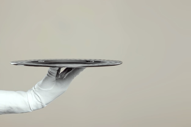 The waiter's hand in white gloves holds a silver tray.