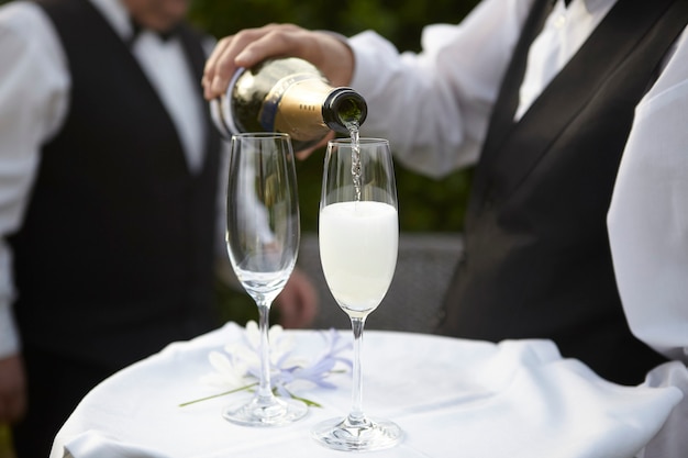 Фото Официант подает шампанское в хрустальном бокале