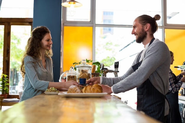 Waiter serving a cup of coffee to customer at counter