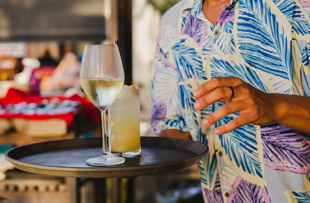 Waiter serving glass of white wine by the glass