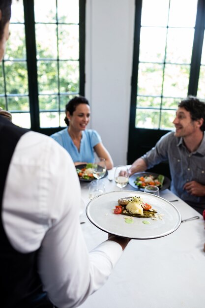 Waiter serving meal to customers