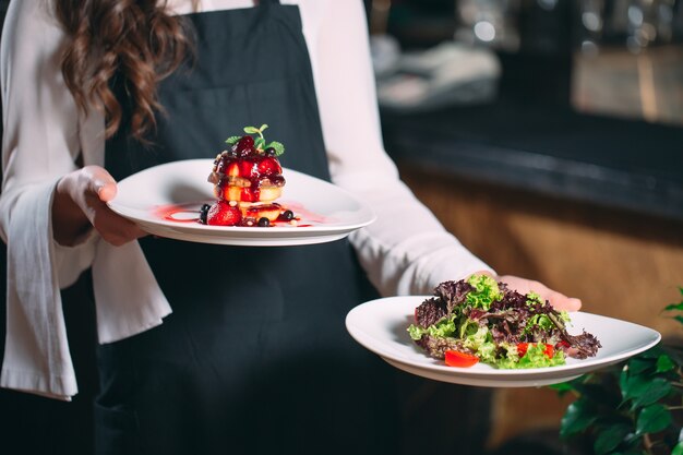 Waiter serving in motion on duty in restaurant. The waiter carries dishes