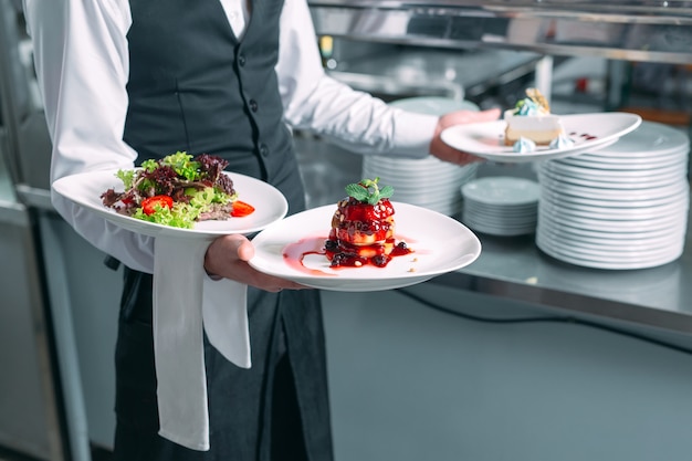 Waiter serving in motion on duty in restaurant. The waiter carries dishes