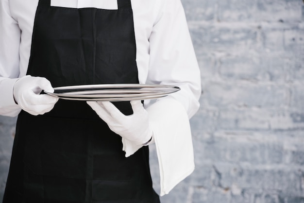 Photo waiter in uniform holding metal tray