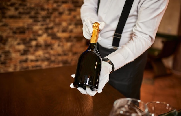 The waiter in uniform offers visitors wine in restaurant