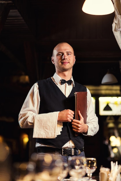 Waiter in uniform with menu waiting an order