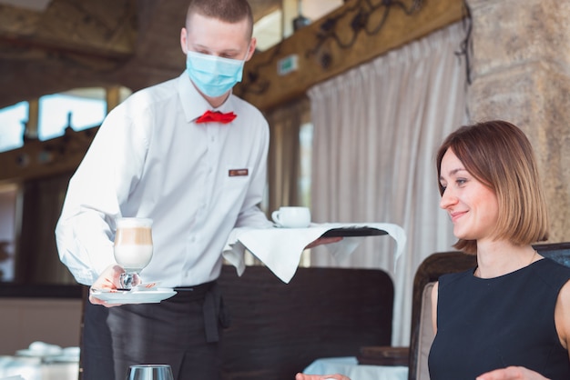 waiter works in a restaurant in a medical mask.