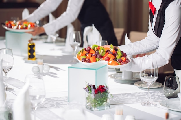 Waiters serving table in the restaurant preparing to receive guests.