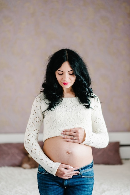 Waiting baby. Pregnant woman standing and hands embraces a round belly