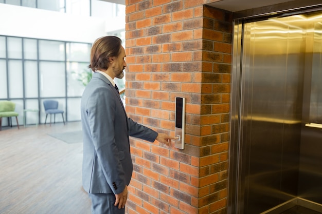 Waiting for elevator. Bearded prosperous businessman waiting for elevator in the business center