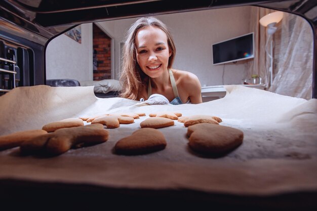 写真 自家製クッキーの準備を待っています。電気オーブンの中からの眺め。美味しいお食事を待っている主婦。プロセスの綿密な監視。