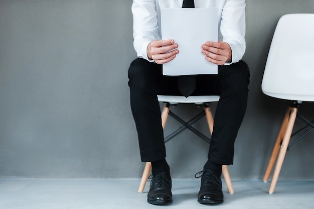 Waiting for interview. Close-up of young man holding paper