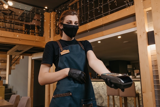 Waitress in black disposable medical gloves wears a medical face mask