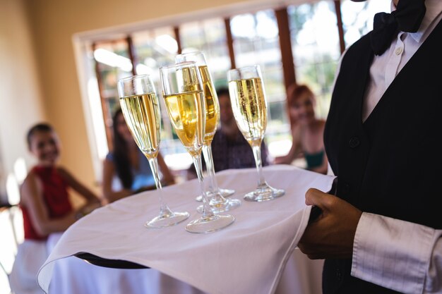 Waitress champagne glasses on tray in restaurant