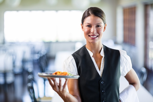 レストランで食事のプレートを保持しているウェイトレス